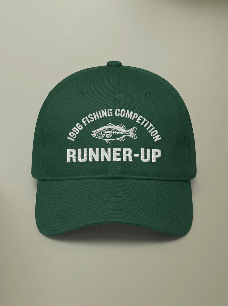 Forest green dad hat embroidered in white with 1996 FISHING COMPETITION curved above a bass, and RUNNER-UP below.