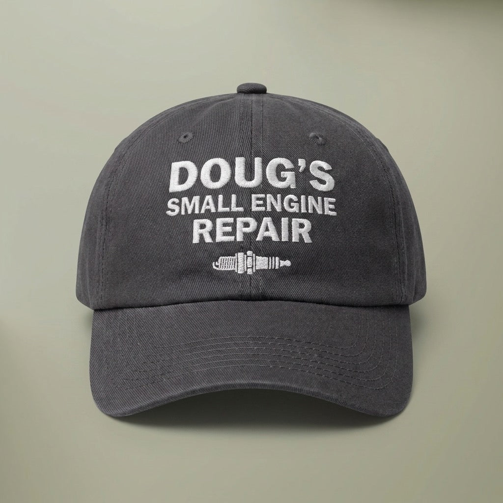 Charcoal grey dad hat embroidered in white with DOUG'S SMALL ENGINE REPAIR above a spark plug.