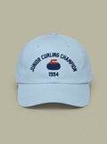 Pale blue dad hat embroidered in navy with JUNIOR CURLING CHAMPION curved above a curling rock, and 1994 below.