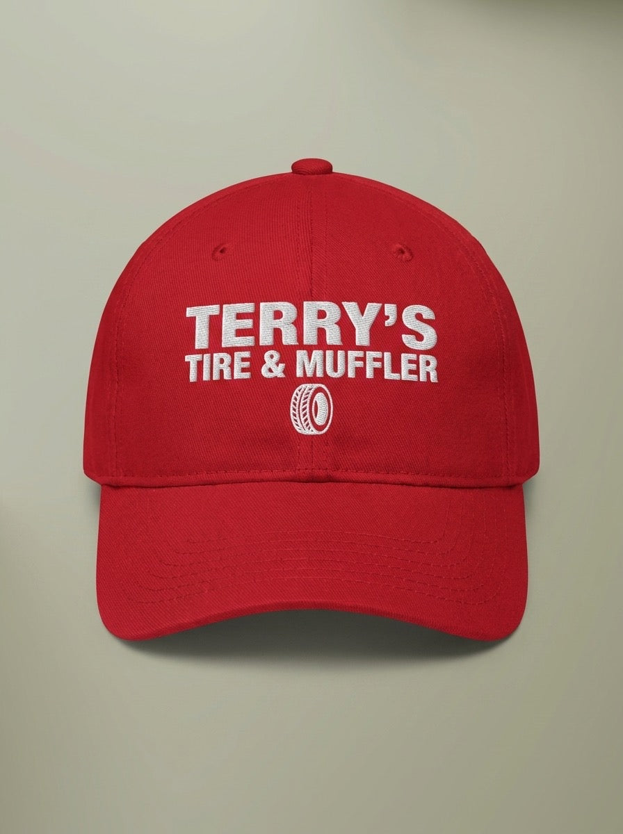 Red dad hat embroidered in white with TERRY'S TIRE & MUFFLER above a tire outline.